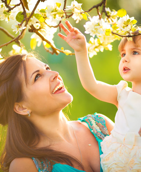 Happy woman and child in the blooming spring garden.Child kissing woman. Mothers day holiday concept